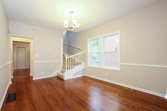 spare room with dark hardwood / wood-style flooring and a chandelier