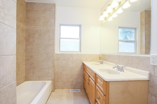 bathroom with vanity, a bathtub, tile patterned floors, and tile walls