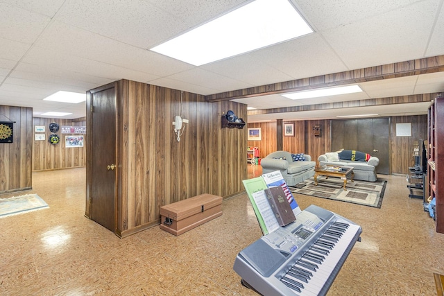 living room with a paneled ceiling and wood walls