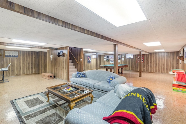 living room featuring a paneled ceiling and wooden walls