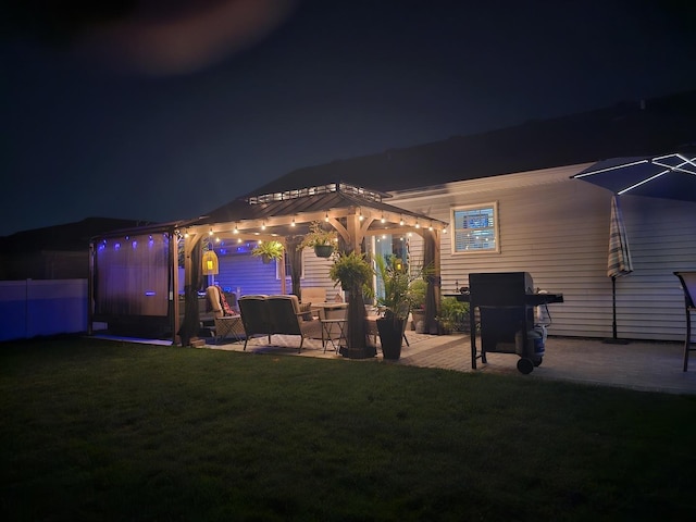 back house at night featuring a pergola, a patio area, and a yard