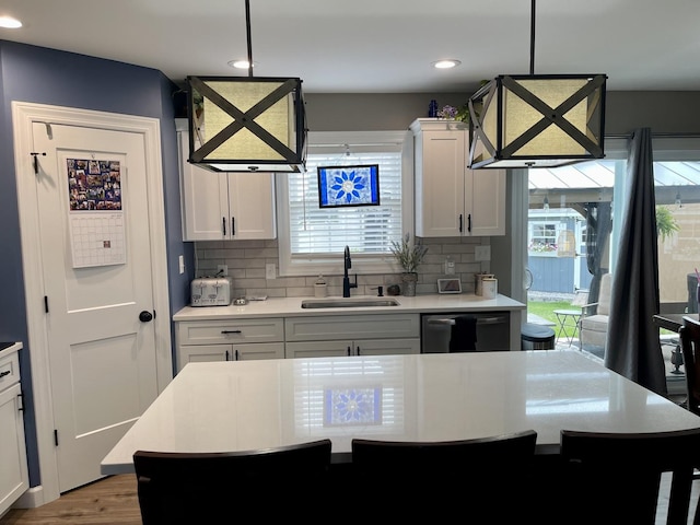 kitchen with pendant lighting, a kitchen island, white cabinetry, and sink