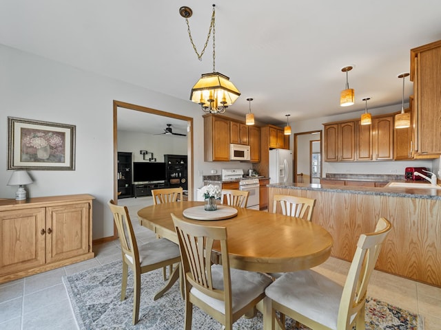 tiled dining space with ceiling fan with notable chandelier and sink