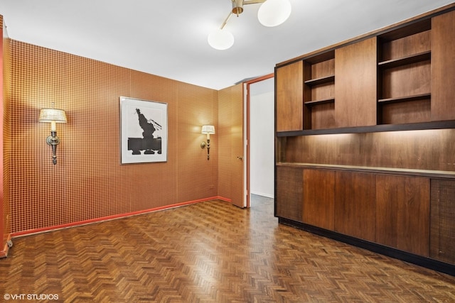 interior space featuring dark parquet flooring, wooden walls, and built in shelves