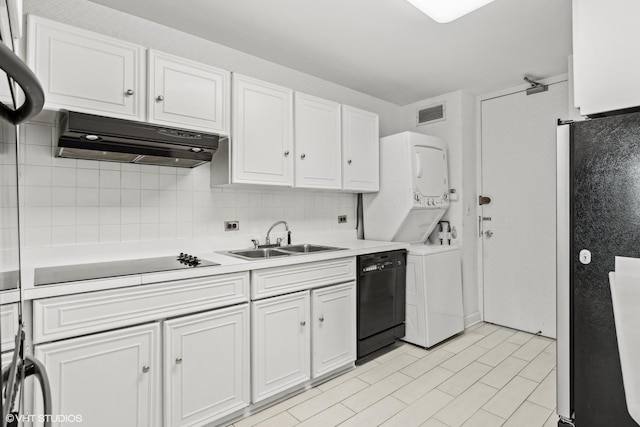 kitchen featuring premium range hood, sink, black appliances, stacked washing maching and dryer, and white cabinets