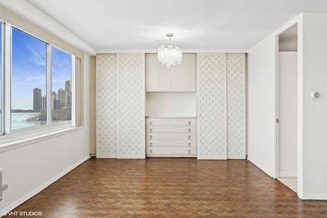 unfurnished bedroom featuring a water view, a notable chandelier, and dark parquet floors