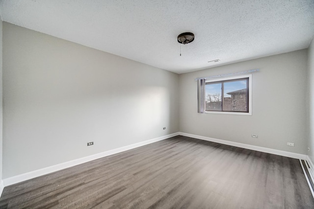 unfurnished room with a textured ceiling and dark hardwood / wood-style flooring