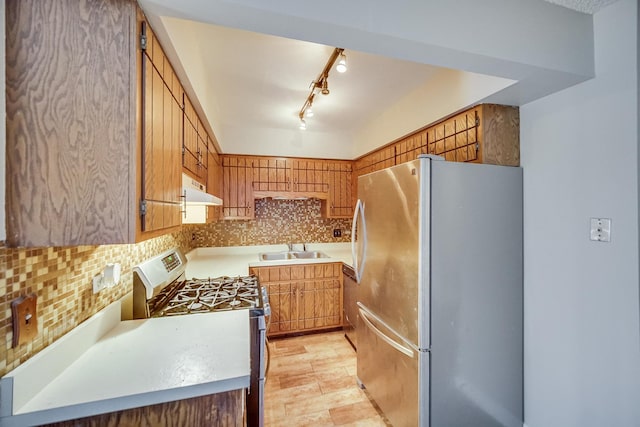 kitchen with decorative backsplash, sink, stainless steel refrigerator, and gas range gas stove