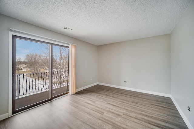 spare room with hardwood / wood-style floors and a textured ceiling