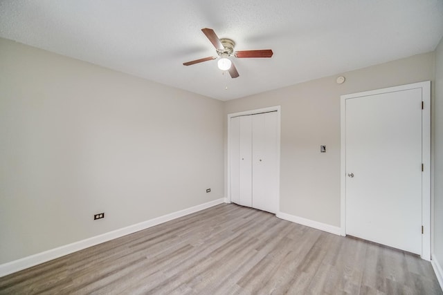 unfurnished bedroom with ceiling fan, a closet, light hardwood / wood-style floors, and a textured ceiling