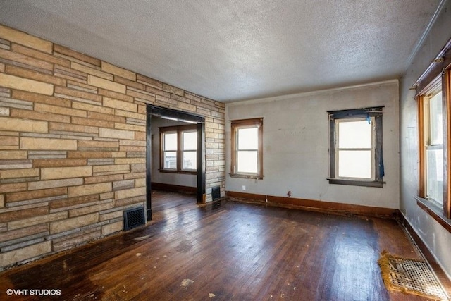 empty room with plenty of natural light, dark wood-type flooring, and a textured ceiling