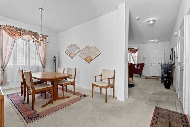 dining room with light colored carpet and a chandelier