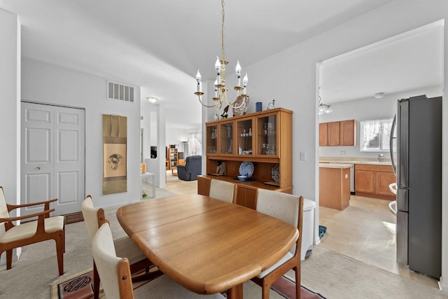 dining room with light tile patterned floors, a chandelier, and sink