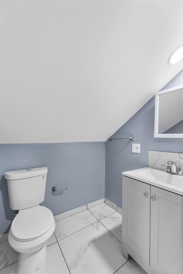 bathroom with vanity, toilet, and lofted ceiling