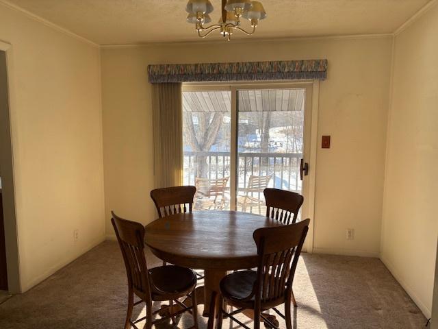 carpeted dining area with an inviting chandelier