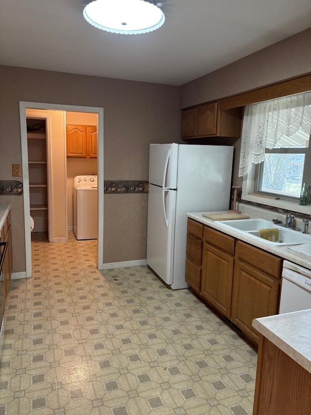 kitchen with white appliances, sink, and washer / dryer