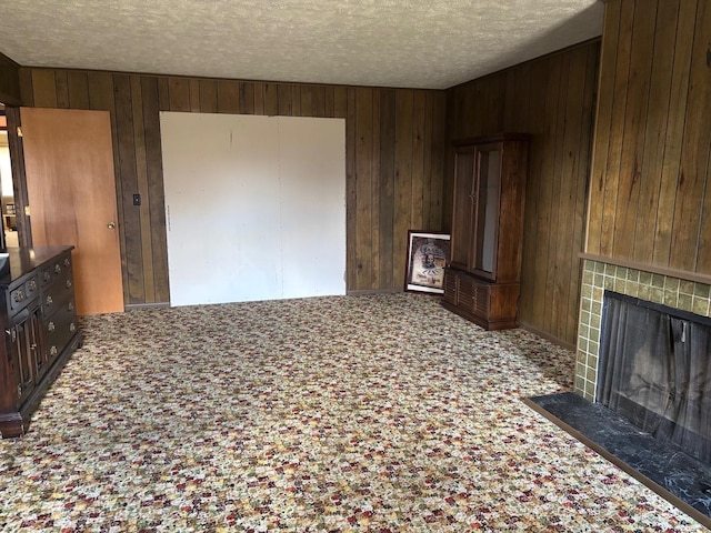 unfurnished living room with a textured ceiling and wooden walls