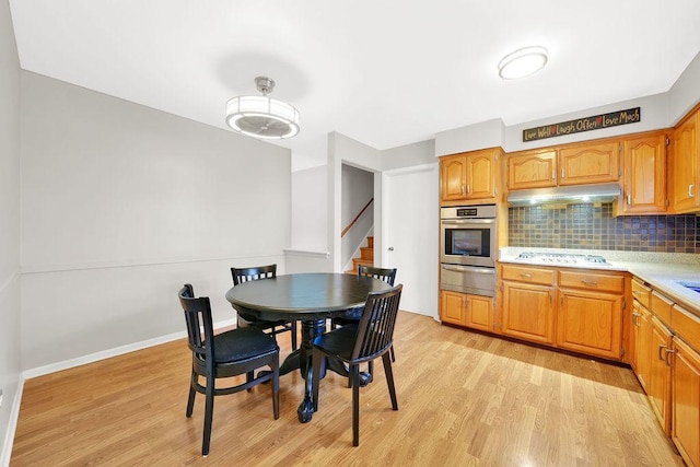 kitchen featuring decorative backsplash, oven, light hardwood / wood-style floors, and white gas cooktop