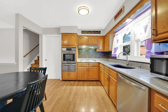 kitchen with stainless steel appliances, tasteful backsplash, light hardwood / wood-style floors, and sink