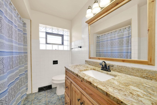 bathroom with tile patterned flooring, vanity, tile walls, and toilet