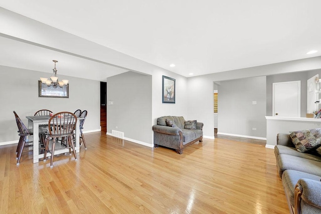 living room featuring light wood-type flooring and a chandelier