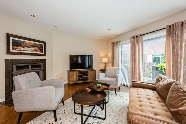 living area with recessed lighting, a fireplace, baseboards, and wood finished floors