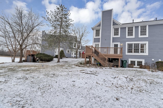 snow covered rear of property with a wooden deck