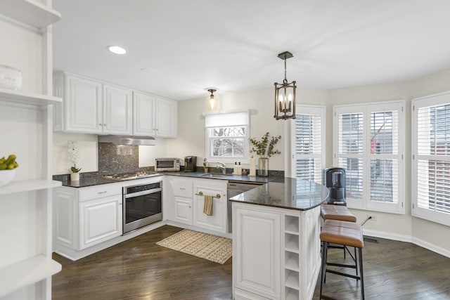 kitchen featuring kitchen peninsula, appliances with stainless steel finishes, sink, decorative light fixtures, and white cabinets