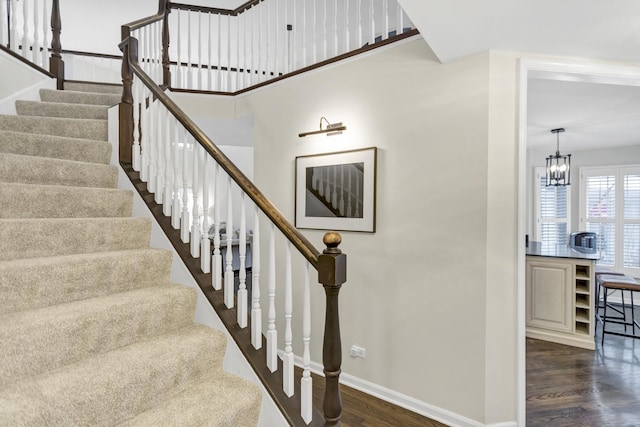 stairway with an inviting chandelier and hardwood / wood-style flooring