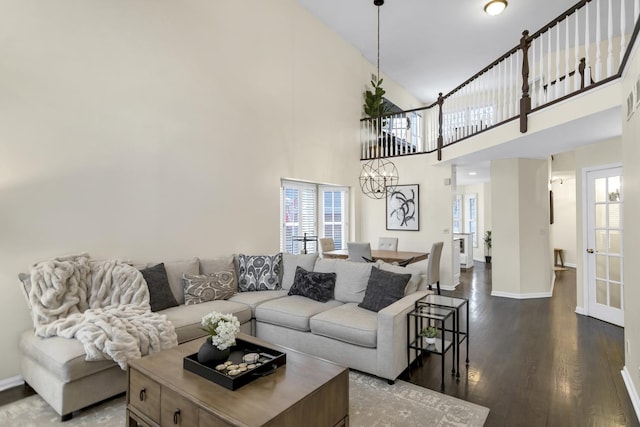 living room featuring a notable chandelier, dark hardwood / wood-style floors, and a towering ceiling