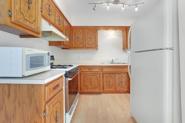 kitchen with sink, white appliances, and light hardwood / wood-style floors