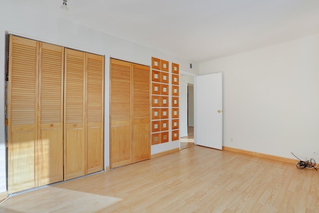 unfurnished bedroom featuring two closets and light hardwood / wood-style floors