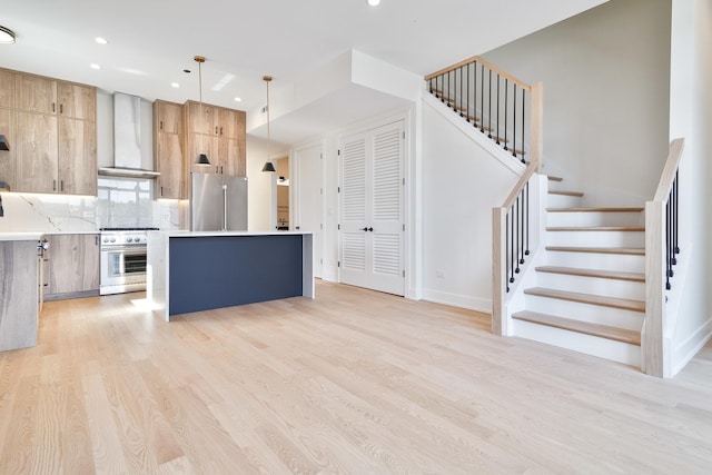 kitchen featuring decorative light fixtures, wall chimney exhaust hood, decorative backsplash, a kitchen island, and high quality appliances