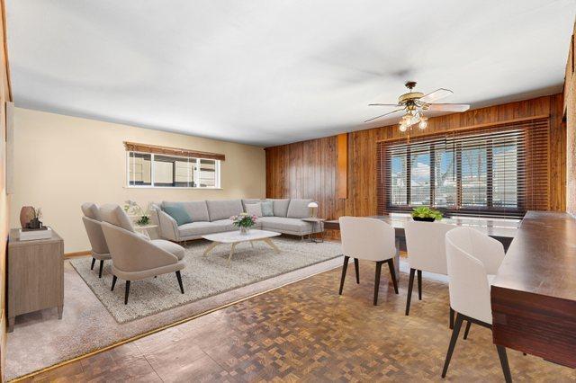 living room with parquet flooring, wooden walls, and ceiling fan