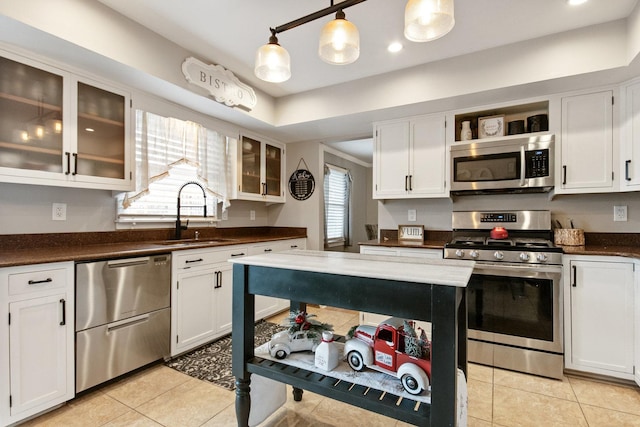 kitchen featuring appliances with stainless steel finishes, sink, light tile patterned floors, pendant lighting, and white cabinets