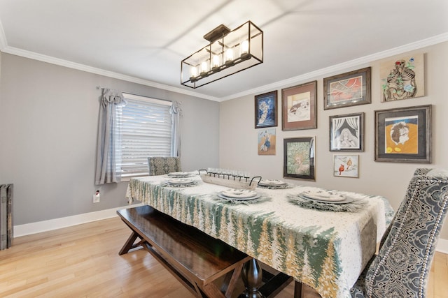 dining space featuring light wood-type flooring, crown molding, and a chandelier