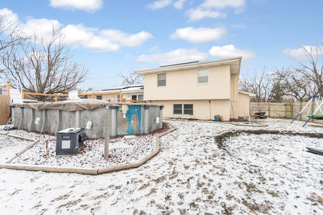 snow covered house featuring a covered pool