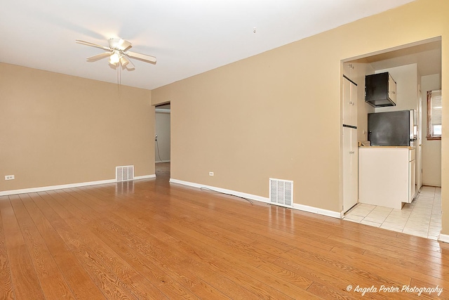 spare room with ceiling fan and light wood-type flooring