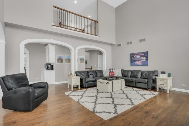 living room featuring hardwood / wood-style flooring, a high ceiling, and decorative columns