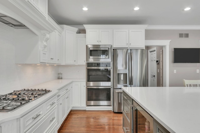 kitchen with wine cooler, white cabinetry, stainless steel appliances, and decorative backsplash