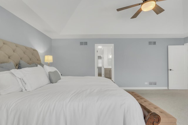 carpeted bedroom with ceiling fan, connected bathroom, and a tray ceiling