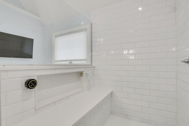 bathroom with ornamental molding and tiled shower