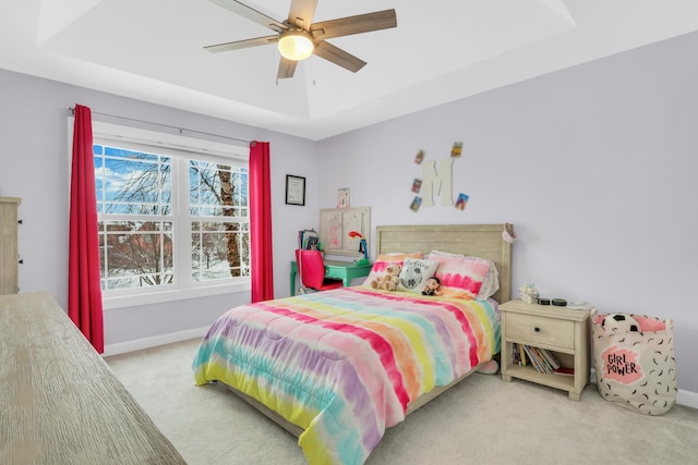 bedroom with ceiling fan, carpet floors, and a tray ceiling