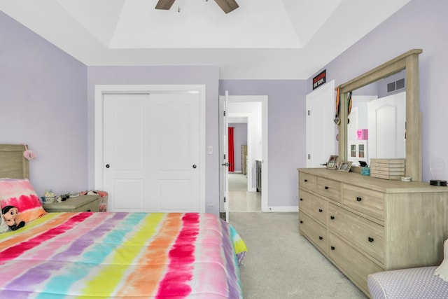 bedroom with ceiling fan, a raised ceiling, light colored carpet, and a closet