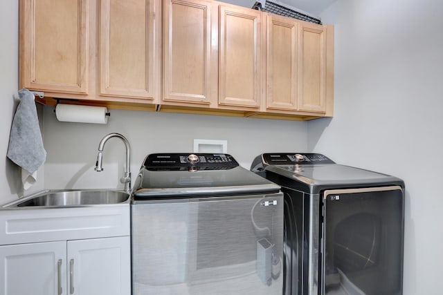 laundry area featuring cabinets, washer and clothes dryer, and sink