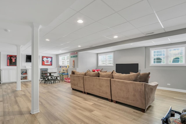 living room with a drop ceiling, light hardwood / wood-style flooring, and decorative columns