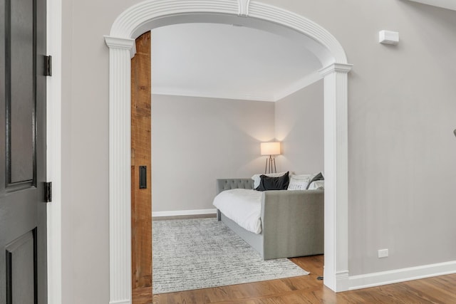 bedroom featuring wood-type flooring, decorative columns, and ornamental molding