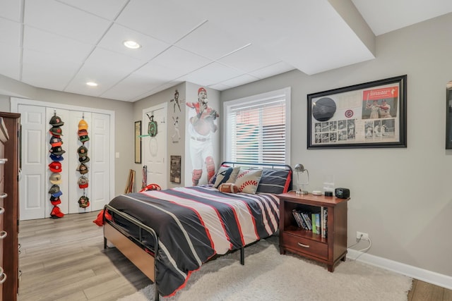 bedroom featuring a paneled ceiling, a closet, and light wood-type flooring