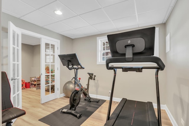 exercise room with french doors, a paneled ceiling, and hardwood / wood-style flooring