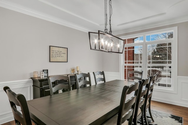 dining space with hardwood / wood-style flooring, crown molding, and an inviting chandelier